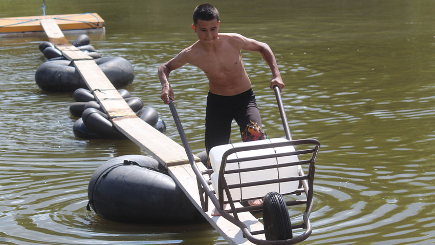 Nejenom plavba v neckách, ale i jízda po lávce s trakařem byla hodně složitá. Foto: Michal Kadlec Neckyáda v Brodku u Konice lákala k rybníku